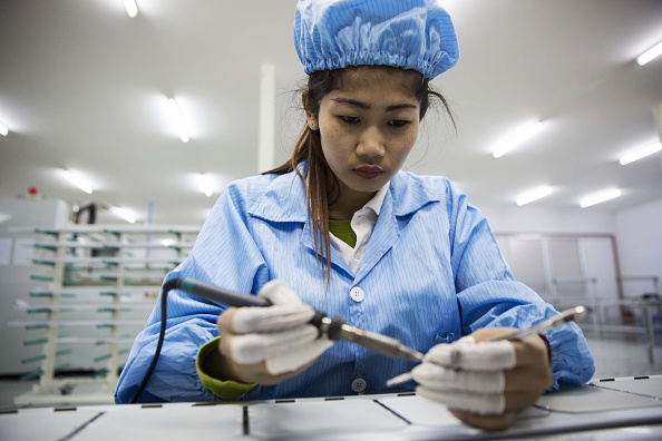 A worker solders solar cell modules at a Star 8 Solar Green Commercial Pty factory in Phnom Penh, Cambodia, on Tuesday, March 8, 2016. Global output from photovoltaics, panels that convert light directly into electricity, has increased 40 percent every year for the past decade. The industry is drawing roughly $150 billion in annual investment, accounting for almost half the funds committed to renewable energy. Photographer: Taylor Weidman/Bloomberg via Getty Images